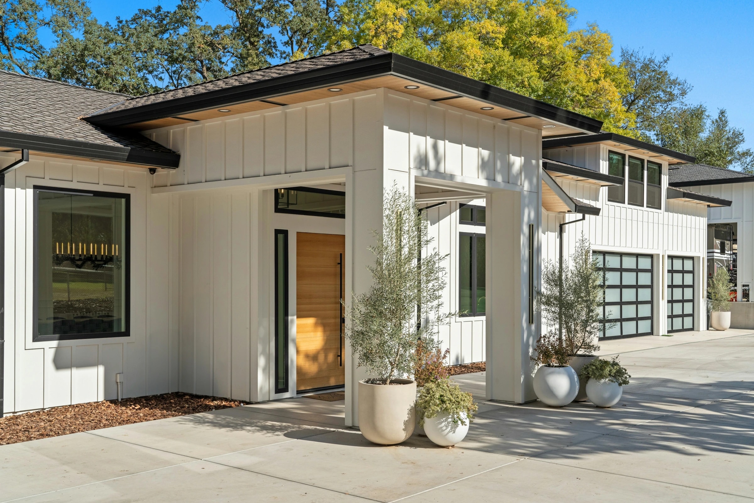 Modern farmhouse with custom glass garage doors and premium exterior finishes